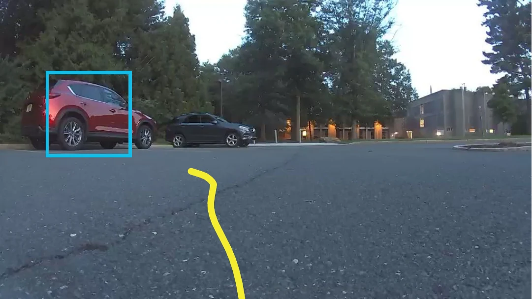 Robot camera view of a parking lot with a red car boxed on the left; the predicted path bends left toward it.